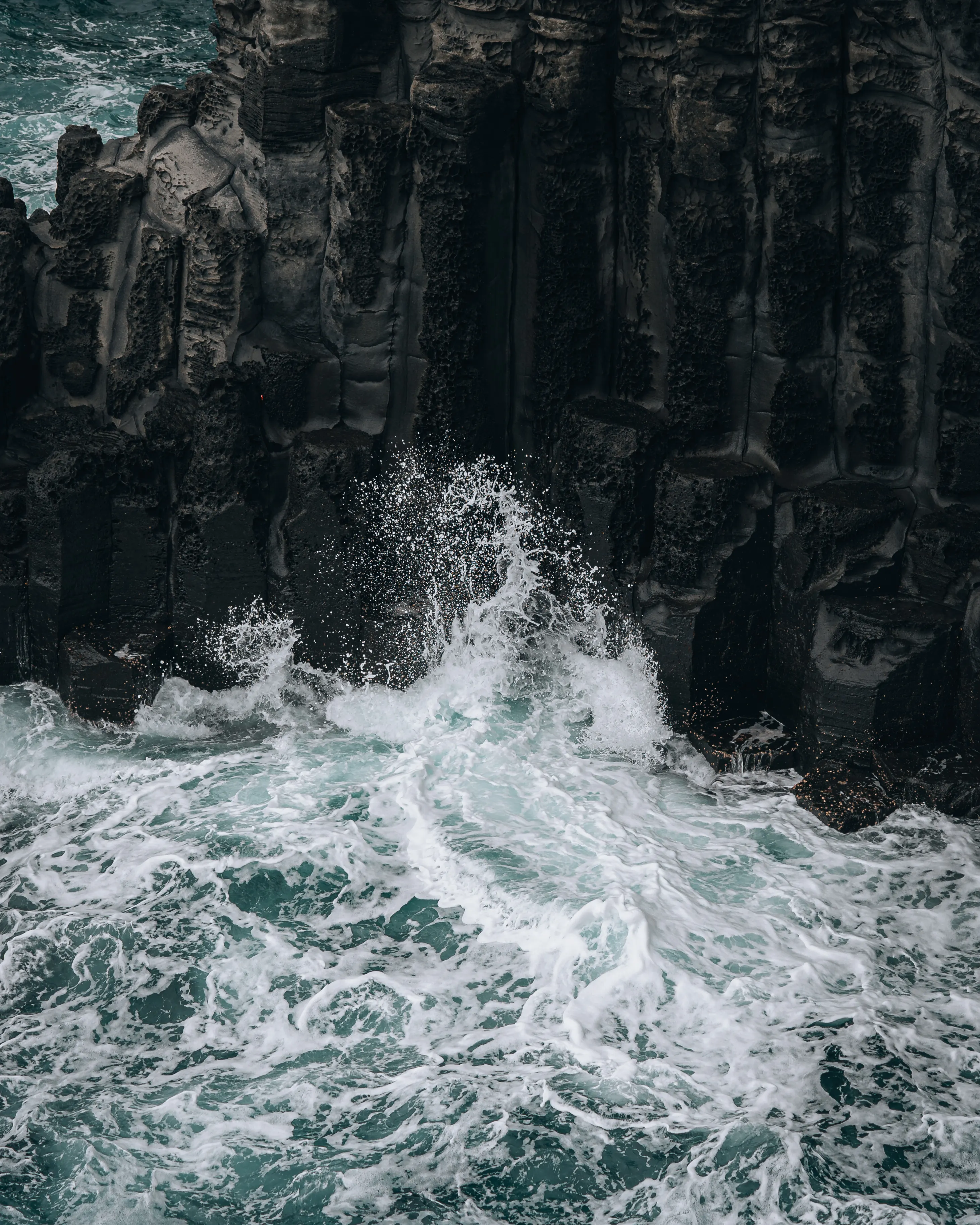 Waves breaking against Jeju volcanic rock